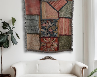 May include: A patchwork tapestry with a variety of patterned squares in shades of red, green, blue, and beige. The tapestry is fringed and hangs on a white wall above a white sofa. A potted plant is to the left.