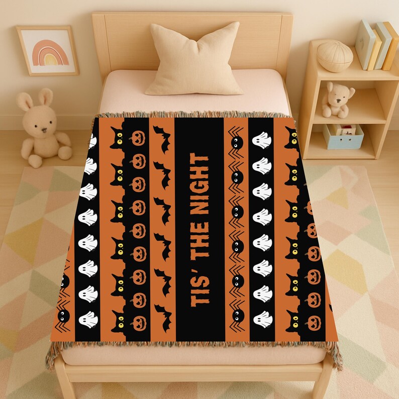 May include: Halloween throw blanket with a black and orange striped design. The blanket features repeating patterns of black cats, jack-o'-lanterns, bats, spiders, and ghosts. The phrase "TIS' THE NIGHT" is printed vertically in the centre.