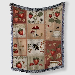 May include: A patchwork throw blanket with a design of strawberries, mushrooms, bees, and teacups. The blanket has a fringed edge and a colour palette of red, cream, and brown. The design evokes a vintage aesthetic.