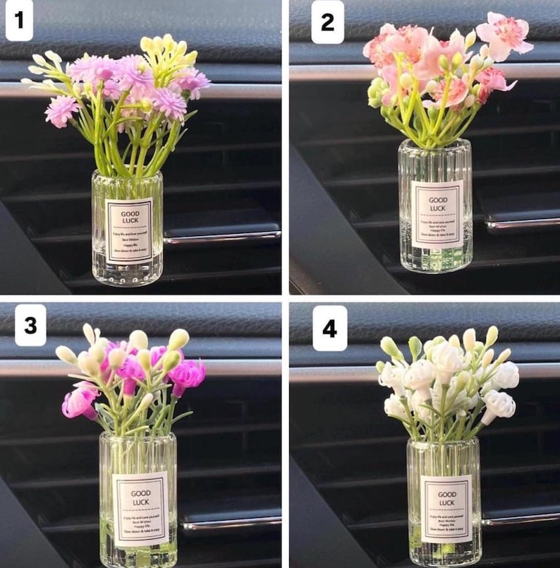 May include: Four car air vent diffusers, each with a different arrangement of artificial flowers in a clear, ribbed glass bottle. Each bottle has a label that reads "GOOD LUCK". The flowers are pink, white, and yellow.