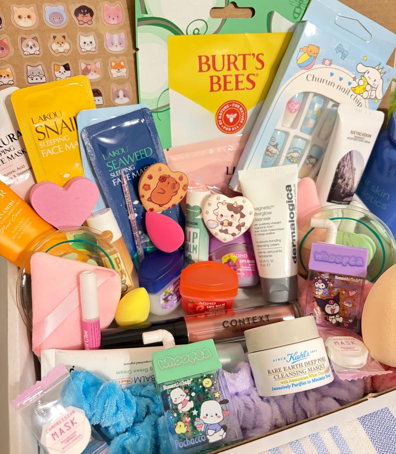 Op de afbeelding: Een verzameling schoonheidsproducten, waaronder gezichtsmaskers, lippenbalsems en huidverzorgingsartikelen. Het assortiment bevat producten van Burt's Bees, Kiehl's en Dermalogica, samen met stickers en nail art. De items zijn gerangschikt in een doos.