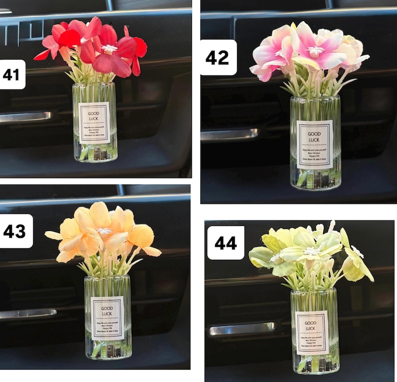 May include: Four small glass vases, each containing a different color of artificial flowers. The flowers are red, pink, yellow, and light green. Each vase has a label that says "GOOD LUCK".