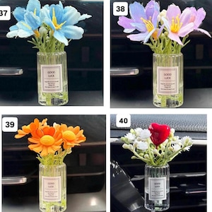 May include: Four small glass vases, each containing artificial flowers. The flowers are blue, purple, orange, and red, with white accents. Each vase has a label that reads "GOOD LUCK".