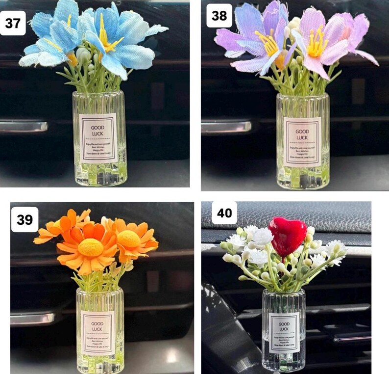 May include: Four small glass vases, each containing artificial flowers. The flowers are blue, purple, orange, and red, with white accents. Each vase has a label that reads "GOOD LUCK".