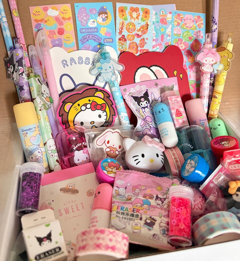 Op de afbeelding: Een doos vol kleurrijke briefpapier en accessoires met stripfiguren. Bevat pennen, stickers, gummen, glitter en notitieboekjes. De items zijn voornamelijk roze, blauw, geel en wit.