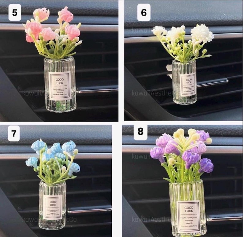 May include: A set of four car air vent diffusers, each featuring a small glass vase with artificial flowers. The vases have a ribbed design and a label that reads "GOOD LUCK". The flowers are pink, white, blue, and purple.