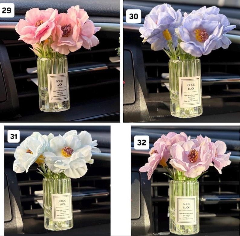 May include: A small glass vase with a label that reads "GOOD LUCK" contains a bouquet of pink flowers. The vase is placed in a car's air vent. The flowers have a realistic appearance.
