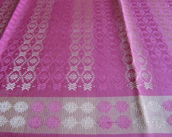 May include: Pink fabric with a white and gold geometric pattern. The fabric has a subtle sheen and a textured surface.