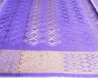 May include: A purple and brown woven mat with a geometric pattern. The mat is made of a thin, flexible material and has a smooth texture.