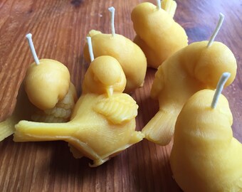 May include: A set of five yellow beeswax candles shaped like birds. Each candle has a white wick.