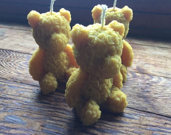 May include: Three yellow beeswax candles shaped like teddy bears. The candles are detailed with a rose pattern.