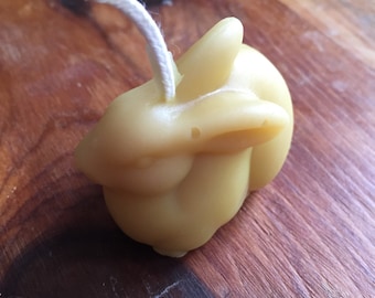 May include: A small, yellow beeswax candle shaped like a rabbit with a white wick.