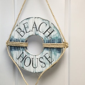 Peut inclure: Panneau de décoration de maison de plage en bois rond, avec une finition blanche et bleue vieillie. Les mots « BEACH HOUSE » sont imprimés en noir. Suspendu par une corde naturelle.