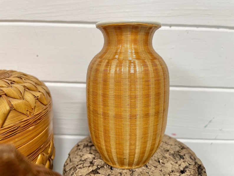 May include: A brown and white striped ceramic vase with a glossy finish. The vase is sitting on a piece of wood.