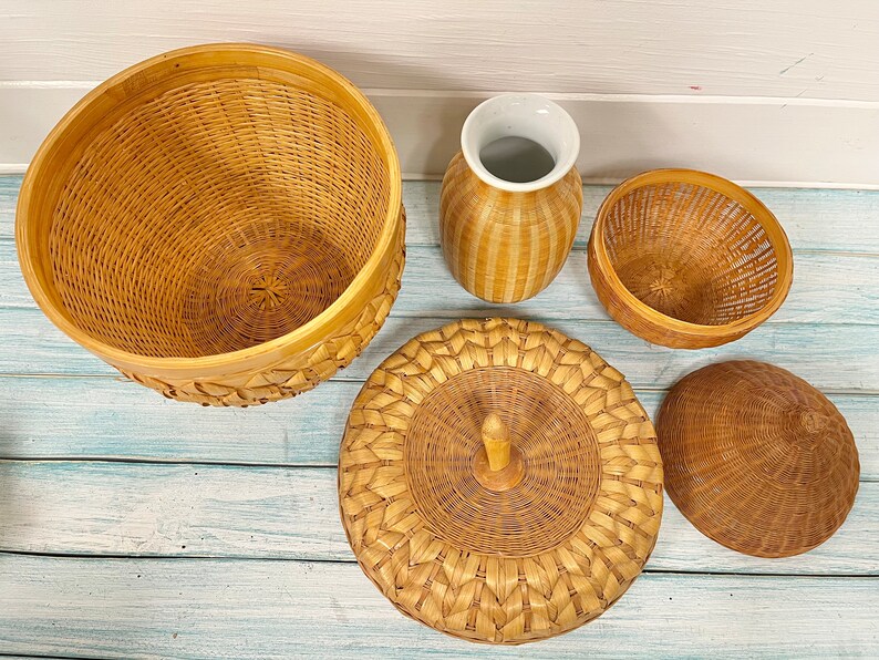 May include: A set of four woven baskets in various shapes and sizes. The baskets are made of natural materials and have a light brown color. The baskets are arranged on a light blue wooden surface.