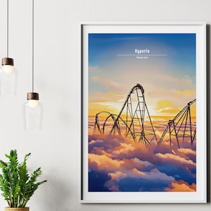 Puede incluir: Una impresión artística enmarcada con un diseño de montaña rusa con el texto "Hyperia, Thorpe Park". La obra de arte representa una montaña rusa contra un cielo al atardecer, con la pista elevándose sobre las nubes. La paleta de colores incluye tonos de azul, naranja y marrón.