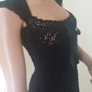 May include: A black crochet dress with a scoop neck and a bow at the neckline.
