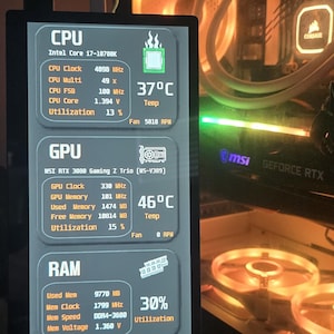 Könnte beinhalten: Ein Computermonitor, der Systeminformationen anzeigt, einschließlich CPU-, GPU-, RAM- und Speichernutzung. Der Bildschirm zeigt Echtzeitdaten wie Taktraten, Temperaturen (37°C und 46°C) und Lüftergeschwindigkeiten an. Datum und Uhrzeit werden ebenfalls angezeigt.