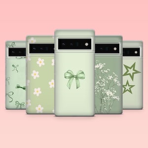 May include: Five pale green phone cases with various designs. One features a bow, another has flowers, a third has white flowers, a fourth has stars, and the last has bows. The cases are arranged in a row against a pink backdrop.