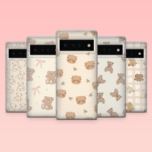 Könnte beinhalten: Fünf Handyhüllen mit Teddybären-Motiv. Die Hüllen haben einen hellbeigen Hintergrund mit verschiedenen Mustern von Teddybären, Schleifen und Umrissen. Die Hüllen sind in einer Reihe vor einem hellrosa Hintergrund angeordnet.