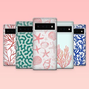May include: Five phone cases with ocean-themed designs. The cases feature coral, starfish, and seashell patterns in red, teal, and blue on a white background. The cases are displayed against a light pink backdrop.