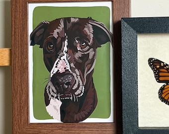 May include: A framed art print featuring a stylized illustration of a brown dog with a white blaze on its face and chest, set against a solid olive green background. The frame is made of brown wood with a textured, linear grain pattern.