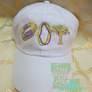 May include: White baseball cap with embroidered purple, green, and gold beads, a purple and gold donut, and a brown tree. The text "DOT" is embroidered on the front of the cap. The cap has a green and white Louisiana state outline with the text "Fine thread Art" in pink.