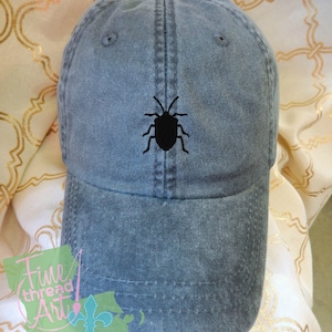 May include: A dark gray baseball cap with a black embroidered bug design on the front.
