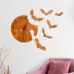 May include: A wooden wall clock with a unique design featuring a clock face with a portion missing, surrounded by wooden bat silhouettes. The clock has black hands and a red second hand, creating a Halloween theme.