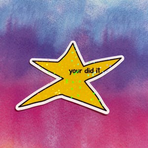 以下が含まれることがあります： 手書きフォントで「your did it」と書かれた黄色の星型ステッカー。星には白い縁取りがあり、キラキラで満たされています。背景は紫、青、ピンクの水彩画です。