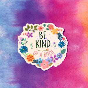 May include: A sticker with a floral wreath design and the text "BE KIND OF A BITCH". The sticker features a variety of colorful flowers and leaves, with a tie-dye background in shades of purple, pink, and orange.