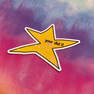 以下が含まれることがあります： 「your did it」という手書きフォントのテキストが入った、黄色の星型のステッカー。ステッカーには白い縁取りと虹色のグリッターアクセントが付いています。背景はピンク、紫、青、黄色のタイダイ模様です。