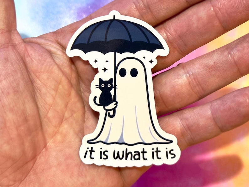 May include: A die-cut sticker featuring a cartoon ghost holding a black umbrella with a black cat. The ghost has two black eyes and is wearing a white sheet. The text "it is what it is" is at the bottom.