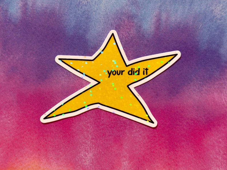 以下が含まれることがあります： 「your did it」の黒い文字が入った黄色の星型ステッカー。星は白い縁取りがあり、キラキラで満たされています。背景は紫とピンクのグラデーションです。