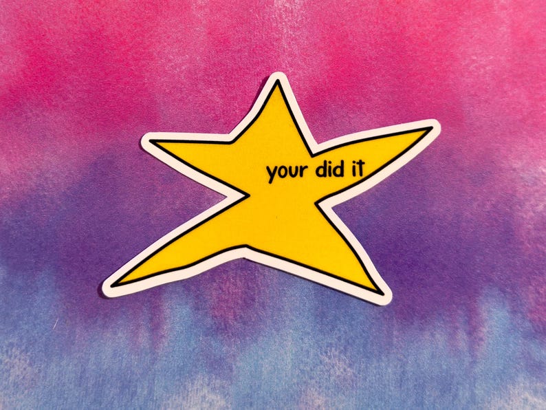 以下が含まれることがあります： 黒いアウトラインと「your did it」という黒い文字が入った黄色の星型のステッカー。ステッカーは、ピンク、紫、青のタイダイの背景に配置されています。