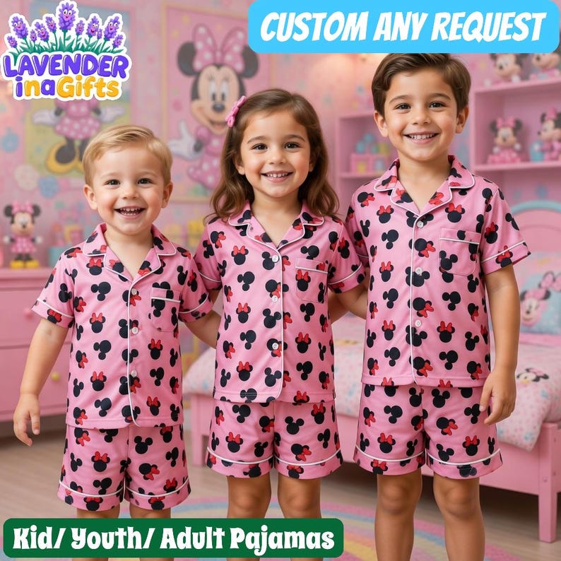 Three children wearing pink pajamas with Minnie Mouse designs are smiling and posing together in a room with a Minnie Mouse-themed decor.