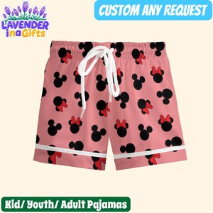A pair of pink shorts with a playful pattern of black Minnie Mouse ears and red bows.