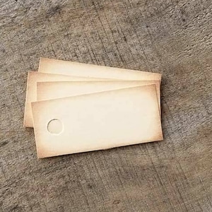 May include: Three vintage-style, rectangular tags with a hole, arranged on a weathered wooden surface. The tags have a cream color with slightly darker edges. The text "SWEETLY SCRAPPED" is printed in white on the wood.
