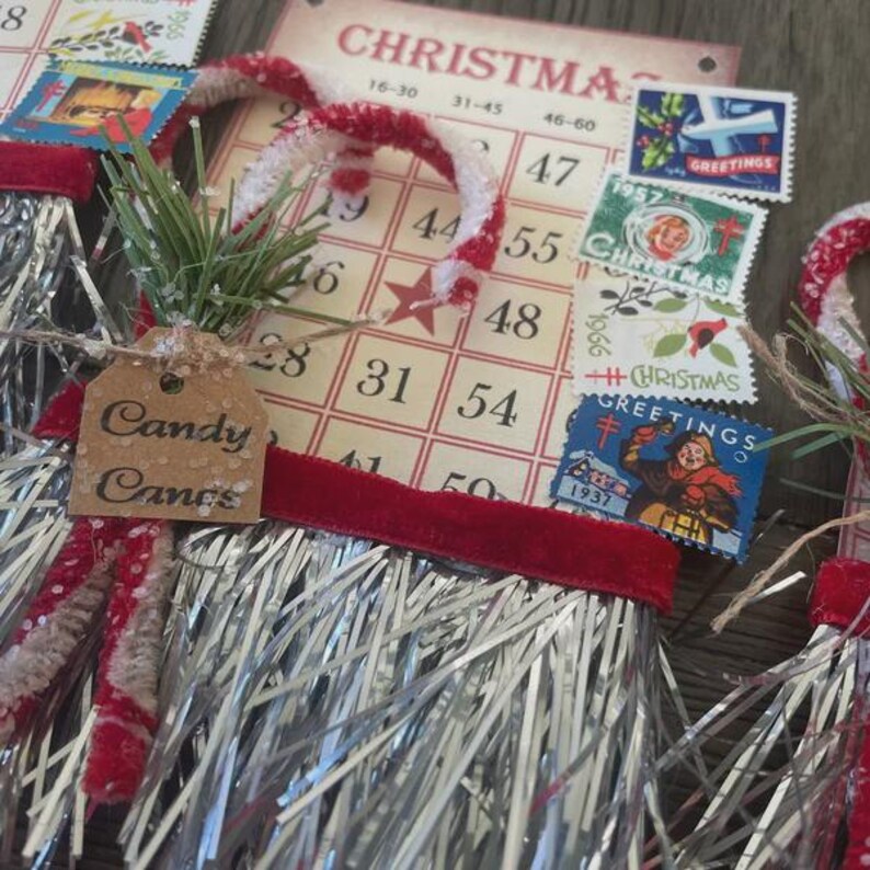 May include: A Christmas-themed craft ornament with a red and white candy cane, silver tinsel, and a red velvet ribbon. The ornament has a brown tag that says "Candy Canes". The ornament is surrounded by vintage Christmas stamps.