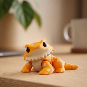 Pode incluir: Figura detalhada de um lagarto laranja e branco com olhos pretos e manchas brancas. A figura está sobre uma superfície de madeira. O lagarto tem uma barriga branca e um design texturizado.