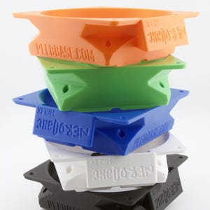 Peut inclure: Une pile d'objets en plastique géométriques colorés en orange, vert, bleu, blanc et noir. Chaque pièce a une forme unique avec le texte "PLEBBBASE.COM" et "NEROJAXE HELIX" imprimé dessus.