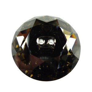 May include: A dark gray, faceted, round button with two holes. The button is made of glass and has a shiny finish.