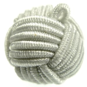 Może przedstawiać: Biała, okrągła, spleciona kula z sznurka z pętlą na górze. Kula wykonana jest z grubego, splecionego sznurka.