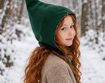 May include: A dark green pointed hood with a colorful patterned lining. The hood is constructed from a solid fabric and features a distinct, elongated peak that extends upward, providing full coverage for the head and neck area.