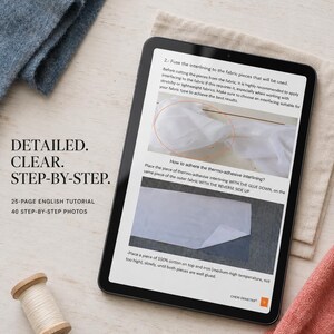 May include: A digital tablet displaying a 25-page English sewing tutorial with 40 step-by-step photos. The screen shows instructions for fusing interlining to fabric, including text and two images. A wooden spool of white thread sits nearby.