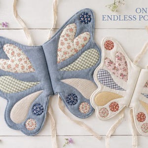 May include: Two fabric butterfly wing costumes with tie straps. The left wing is blue with floral, gingham, and striped patches. The right wing is cream with similar patterned patches. Text reads: ONE PATTERN, ENDLESS POSSIBILITIES.