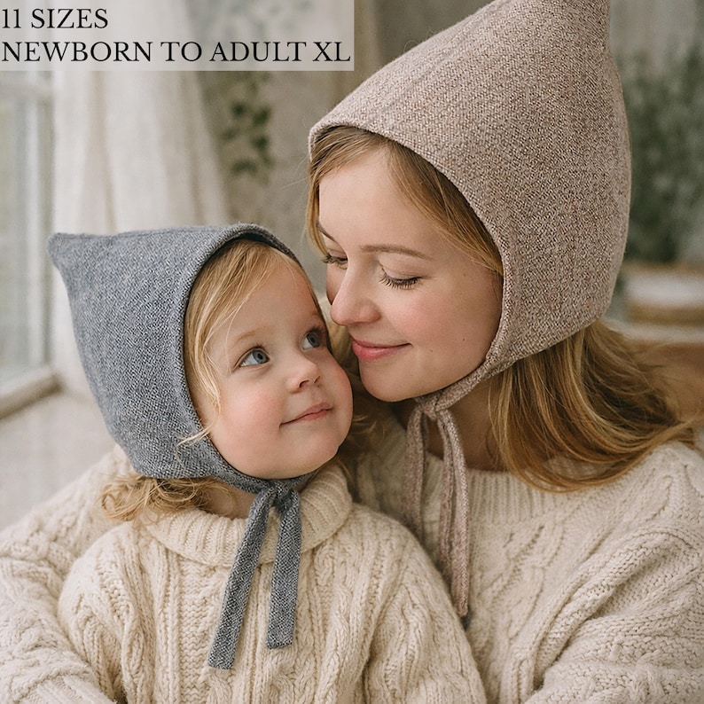 May include: Two knit bonnets with pointed tops and chin ties. One bonnet is heather gray, and the other is a light beige. The text 11 SIZES NEWBORN TO ADULT XL is visible in the upper left corner. These head coverings feature a textured knit fabric.