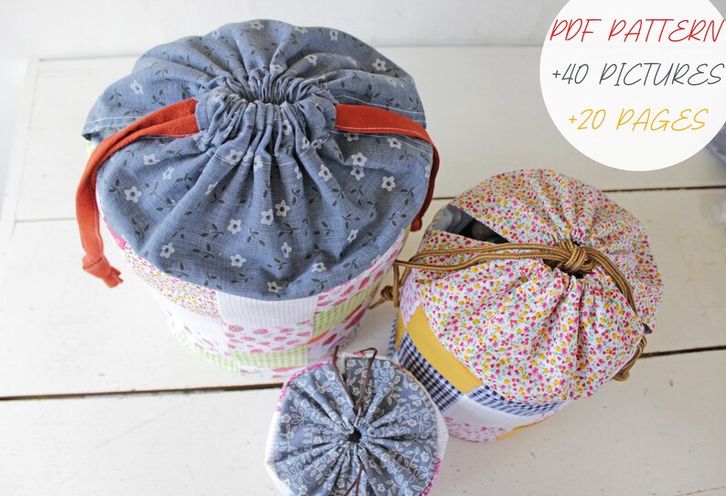 May include: Three drawstring bags made of patchwork fabric. The bags are in various sizes and feature different floral patterns. The largest bag is blue with white flowers, the medium bag is white with pink and yellow flowers, and the smallest bag is blue with white flowers. The bags are all tied with a drawstring.