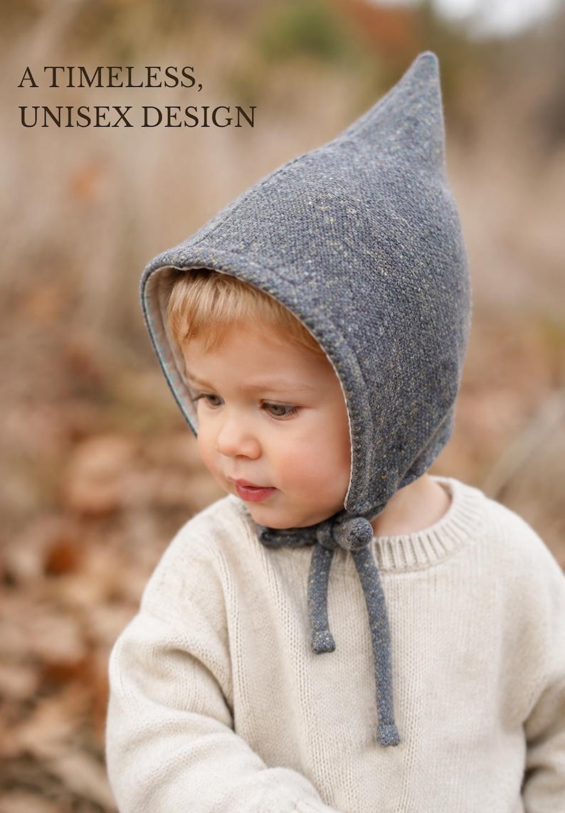 May include: A grey speckled pointed bonnet with a light-colored interior lining and tie closures under the chin. The text A TIMELESS, UNISEX DESIGN is visible in the upper left corner of the image. The bonnet features a textured fabric finish.