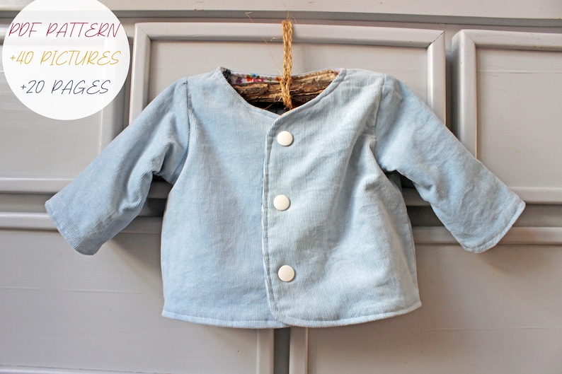 May include: A light blue long-sleeve jacket with three white buttons down the front. A circular white graphic in the top left corner contains the text PDF PATTERN +40 PICTURES +20 PAGES. The jacket is hung on a rustic wooden hanger.